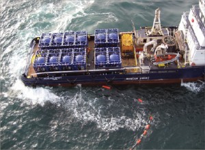 A boat using “slider tanks” transports cuttings to shore for further treatment and disposal in the North Sea. The cuttings were blown from a rig without the use of a crane. A transfer line floats in the water.