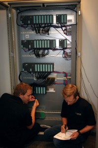 Technicians interface the HIL simulators to the control system replica PLC rack in the HIL testing lab. Setting up the HIL lab involves connecting a vessel’s main control systems to a simulated rig that is an exact replica of the actual vessel, which establishes a virtual world for the control systems to interact. Source: Øyvind Smogeli