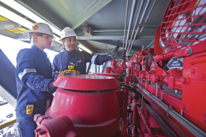 BHP operations engineers inspect equipment on a new H&P FlexRig 5 in the Eagle Ford. BHP is reducing its North American land operations next year from 40 rigs to 26, which is expected to help the company focus on safety and operational performance.