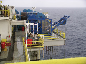 The umbilical winch, which extends over the side of the rig, raises and lowers the pumps to the seabed and serves as a conduit for power and communication. 