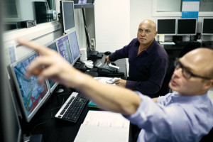 Maersk Training instructors Kim Noe (front) and Denis Edmonds (back) observe student behaviors and actions from the control room behind the drilling simulator during a technical exercise. 