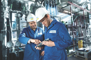 : DNV GL – Oil and Gas workers inspect testing devices at a sand test laboratory. The company’s updated recommended practice provides a set of guidelines to manage sand through the life of a well and promotes making the best use of available technologies and methods.