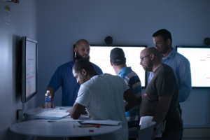 Robert Howell (back right), a technical instructor with Maersk Training, helps students from Rowan start a well control simulator exercise on 22 July in Houston. In the five-day course, students split their time between the classroom and the simulator, with human factors built directly into the technical training. 